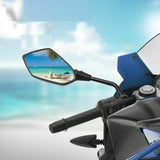 A motorcycle with side mirrors, set against a beautiful beach and ocean backdrop.
