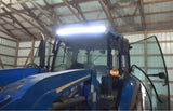 A tractor with lights on, showcasing its LED light bar, inside a rustic barn setting.